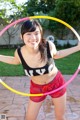 A young woman holding a hula hoop in her hands.