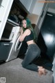 A woman kneeling on the floor in front of a washing machine.