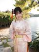 A woman in a pink kimono standing next to a body of water.