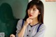 A woman sitting in front of a blackboard with her hand on her chin.