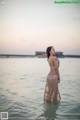 A woman standing in the water with her back to the camera.