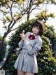 A girl in a school uniform holding a flower in her hand.