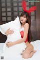 A woman in a red bunny costume sitting on a bed.