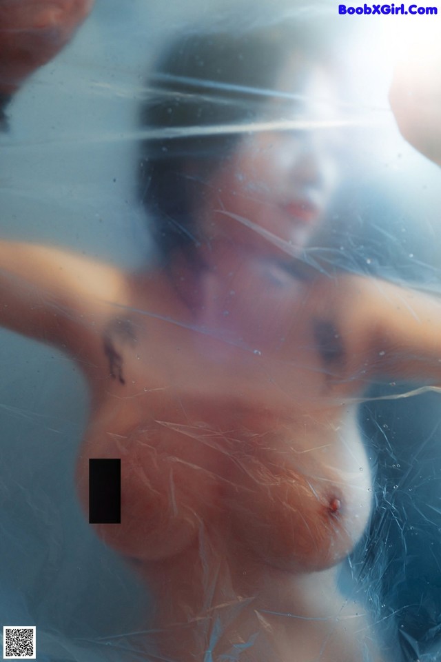 A woman is covered in plastic with her hands behind her head.