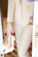 A woman in a white suit holding a pair of white shoes.