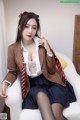 A woman in a school uniform sitting on a white chair.