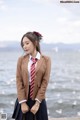 A woman in a school uniform standing by the water.