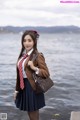 A woman in a school uniform standing by the water.