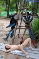 A naked woman laying on the ground next to a robot.