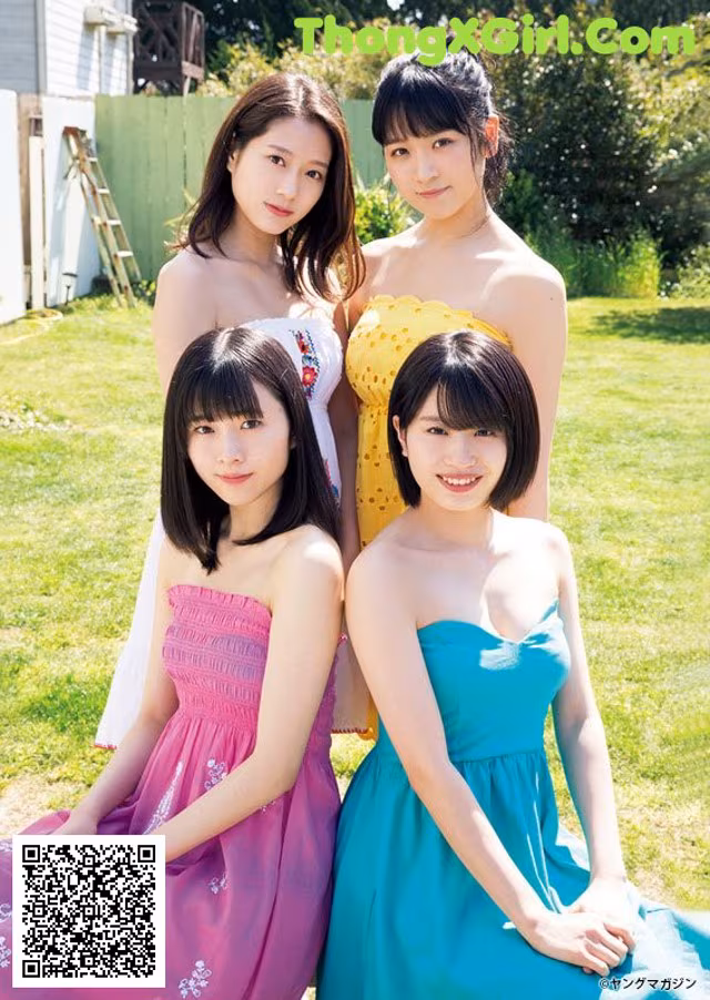 A group of young women sitting on top of a lush green field.