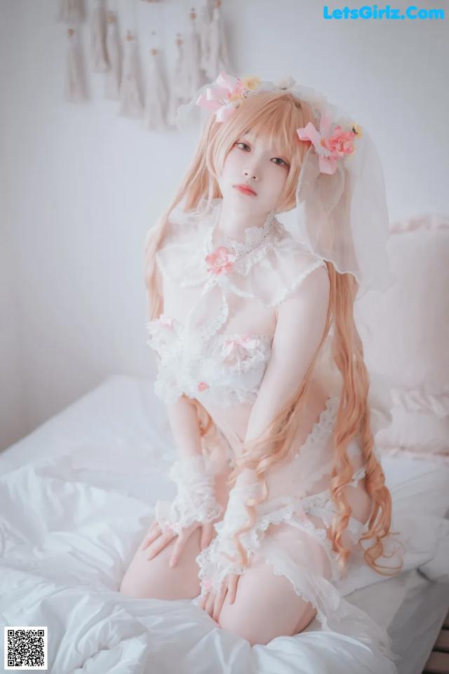 A woman in a white lingerie sitting on a bed.