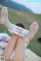 A woman in white stockings is laying on a blanket.