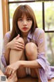 A woman sitting on a window sill with her legs crossed.