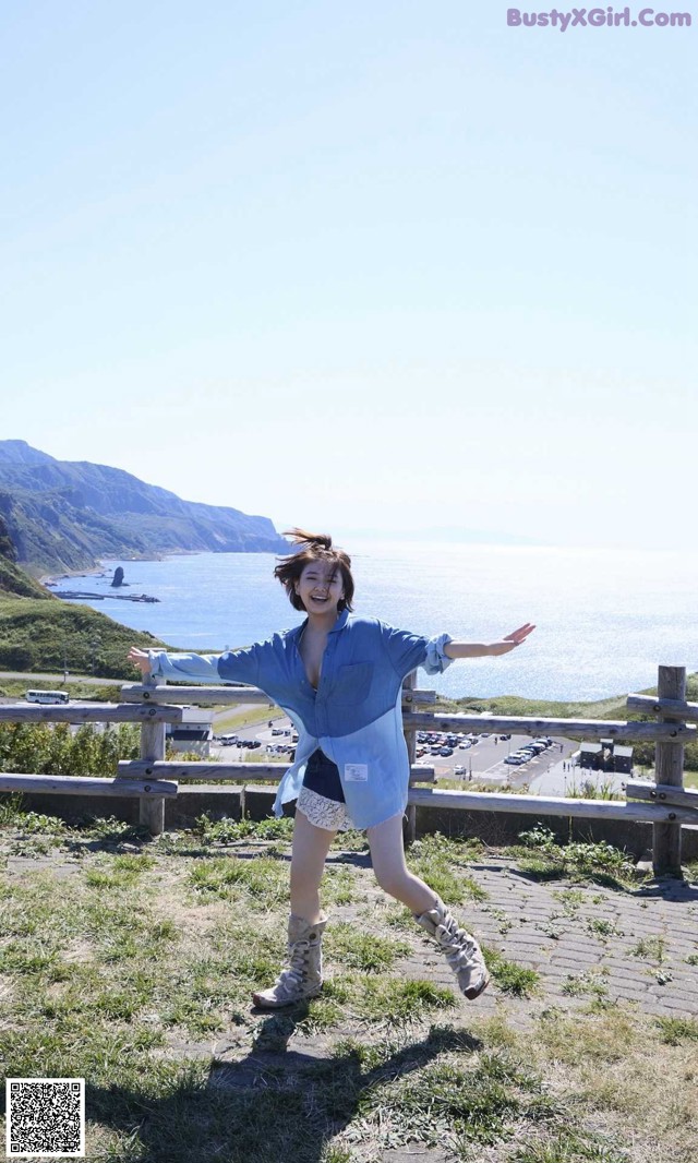 A woman standing on top of a hill with her arms outstretched.
