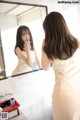 A woman in a white dress looking at herself in the mirror.