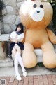 A woman sitting next to a giant teddy bear.