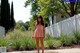 A young woman standing in front of a white fence.