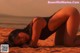 A woman in a black bathing suit laying on the beach.