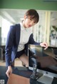 A woman in a business suit sitting at a desk with a computer.