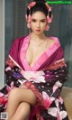 A woman in a pink and black kimono sitting on a couch.