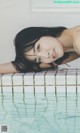 A woman laying on the edge of a swimming pool.