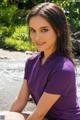 A woman in a purple shirt sitting on the ground.