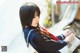 A woman in a school uniform sitting on a bench.