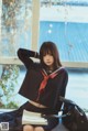 A woman in a school uniform sitting on a window sill.