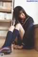 A woman in a school uniform sitting on the floor.