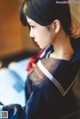 A woman in a sailor outfit sitting on a bed.