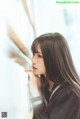 A young woman leaning against a wall with her hand on her chin.