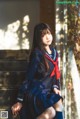 A woman in a school uniform sitting on some steps.