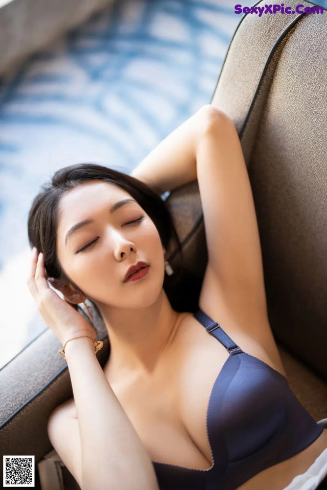 A woman in a blue bra laying on a couch.
