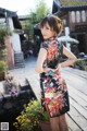 A woman in a black and red floral dress posing for a picture.