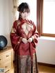 A woman in a red kimono standing in front of a window.