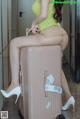 A woman sitting on top of a pink suitcase.